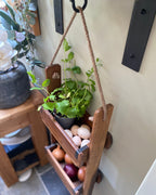 Wooden hanging basket with plants and eggs on a kitchen counter.