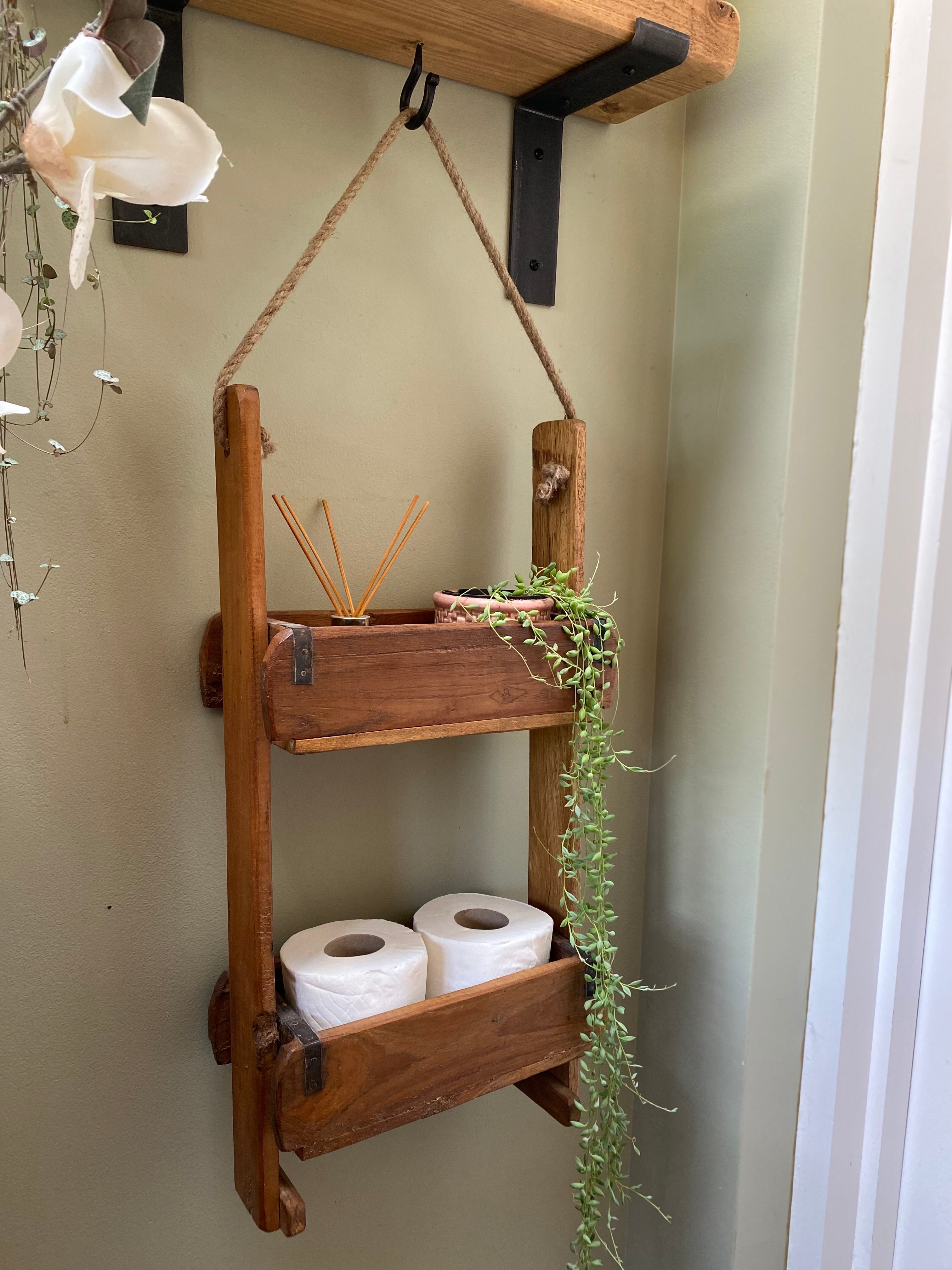 Wooden wall shelf with toiletries and a plant against a light-colored wall.